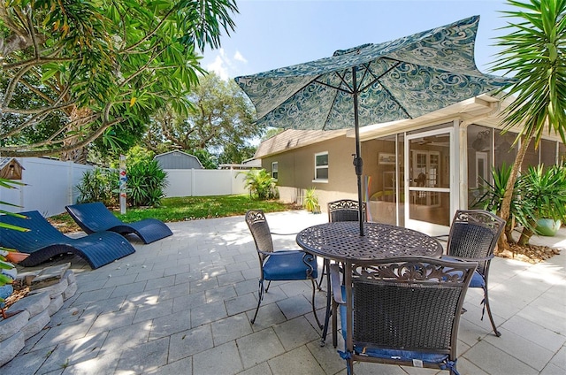 view of patio with a sunroom, outdoor dining area, and a fenced backyard