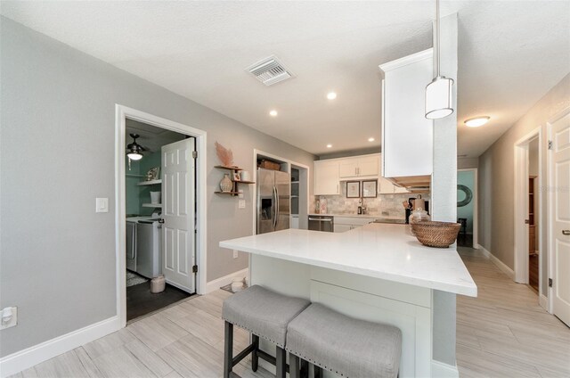 kitchen featuring a kitchen breakfast bar, tasteful backsplash, a peninsula, baseboards, and appliances with stainless steel finishes