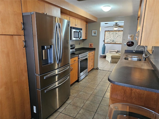 kitchen featuring light tile patterned flooring, sink, ceiling fan, stainless steel appliances, and a textured ceiling