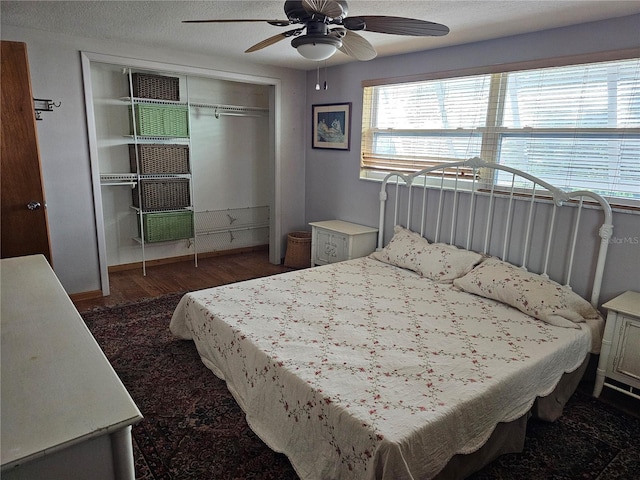 bedroom featuring dark hardwood / wood-style flooring, a textured ceiling, ceiling fan, and a closet