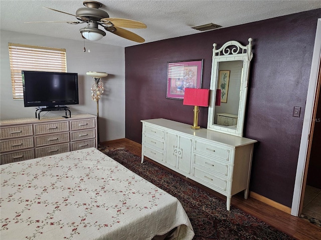 bedroom featuring dark hardwood / wood-style flooring, ceiling fan, and a textured ceiling