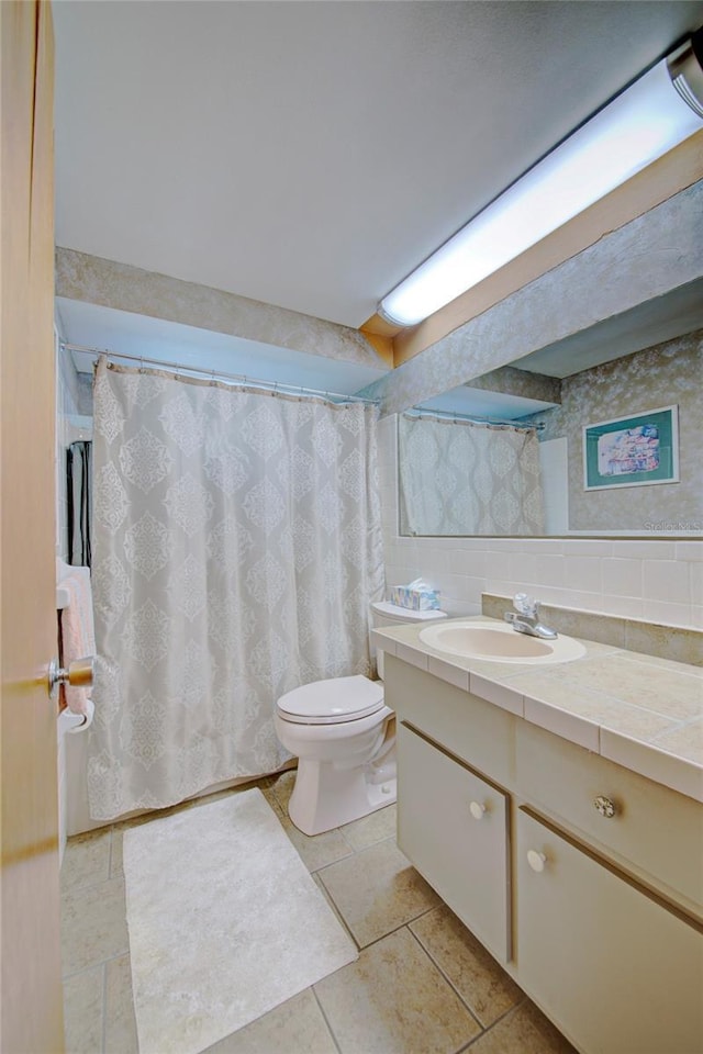 bathroom with tasteful backsplash, vanity, tile patterned flooring, and toilet