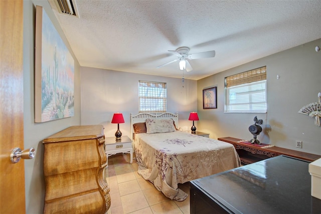 bedroom featuring ceiling fan, light tile patterned floors, and a textured ceiling