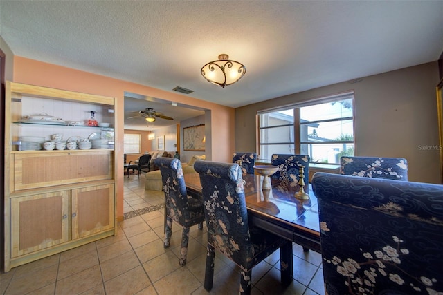 dining space with ceiling fan, a textured ceiling, and light tile patterned flooring