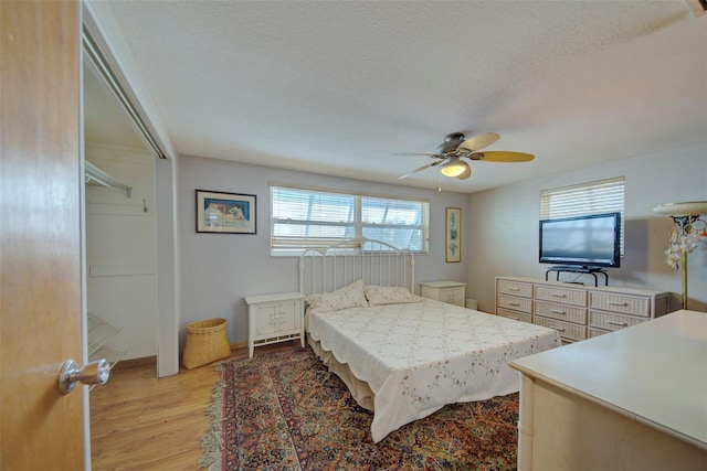 bedroom with ceiling fan, light hardwood / wood-style floors, a closet, and a textured ceiling