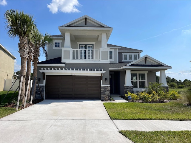 view of front facade featuring a balcony, a garage, and a front yard