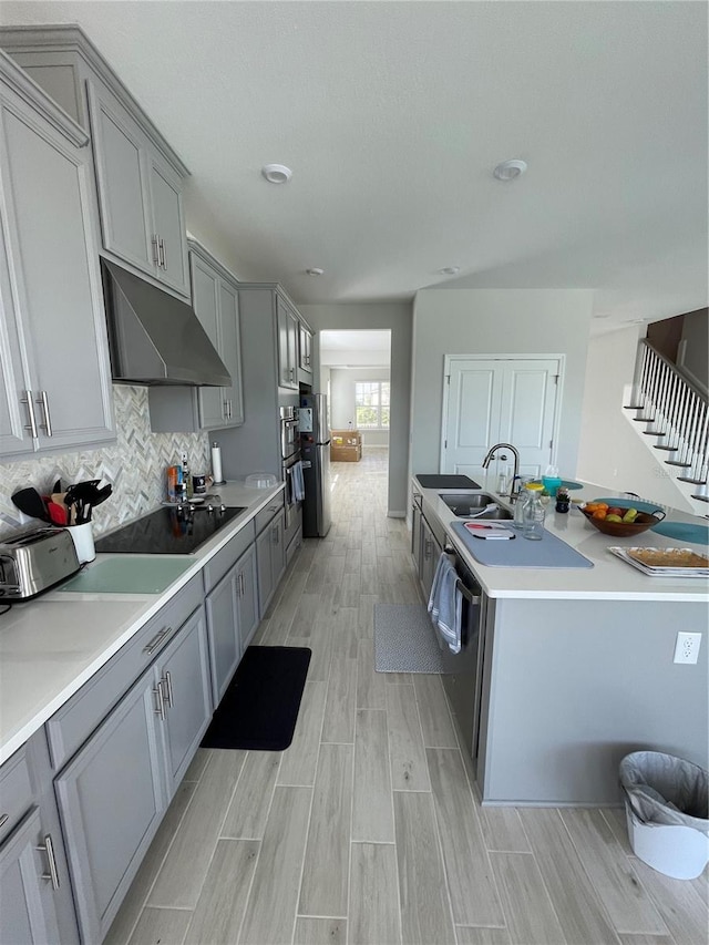 kitchen with stainless steel appliances, sink, gray cabinets, and decorative backsplash