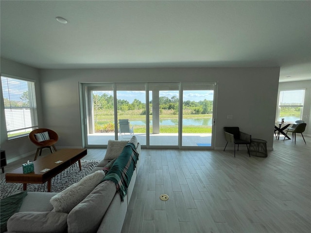 living room with a water view, a wealth of natural light, and light wood-type flooring