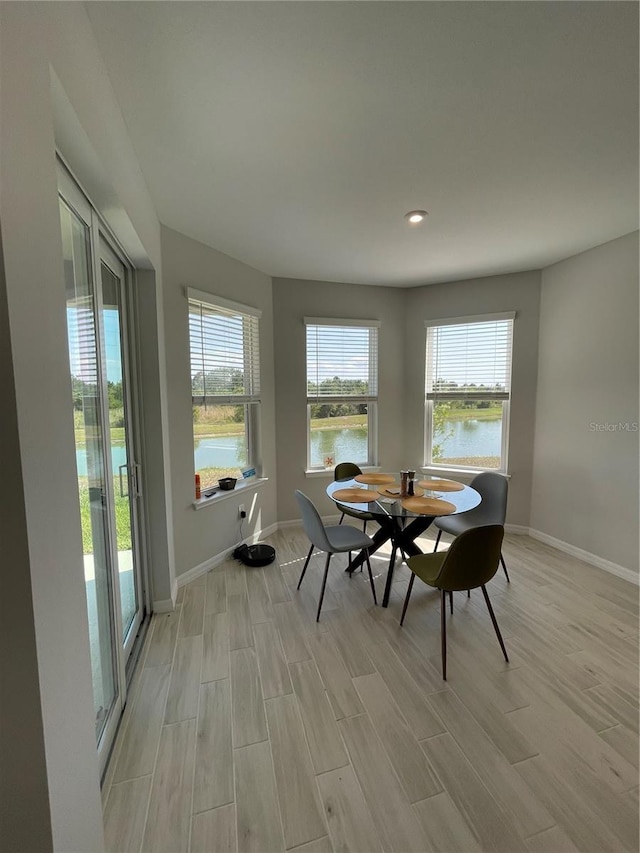 dining area featuring a water view, a wealth of natural light, and light hardwood / wood-style floors