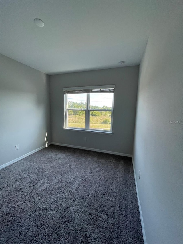 unfurnished room with dark carpet