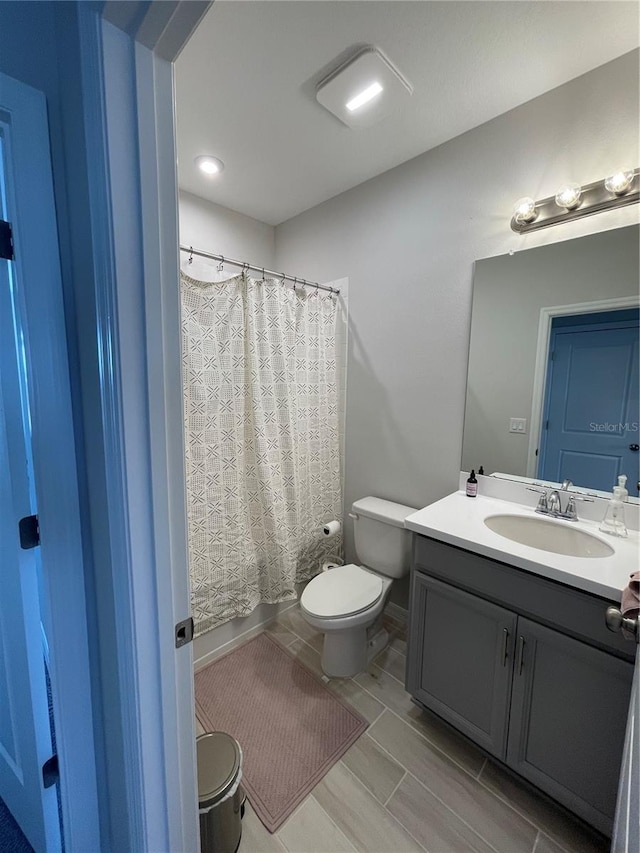 bathroom featuring vanity, curtained shower, and toilet