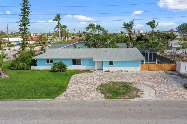 ranch-style house with decorative driveway, stucco siding, a front yard, glass enclosure, and fence