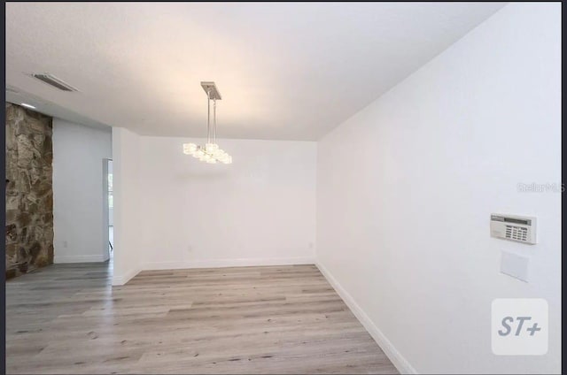 unfurnished dining area with light hardwood / wood-style floors and a chandelier