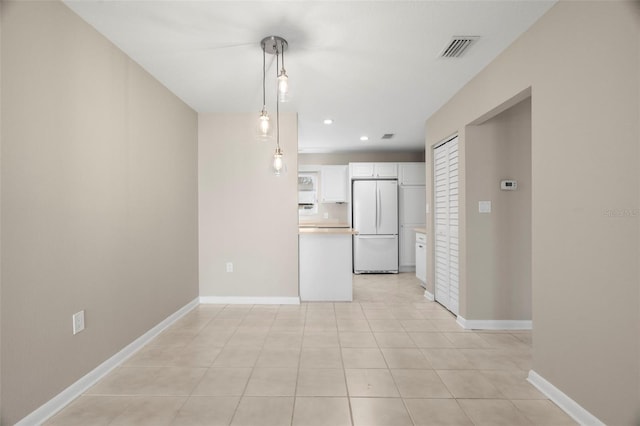 kitchen with white cabinetry, decorative light fixtures, light tile patterned flooring, and white fridge