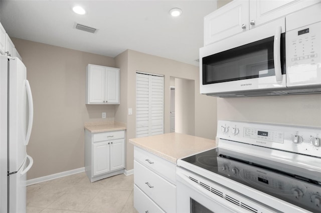 kitchen with white cabinetry, light tile patterned flooring, and white appliances