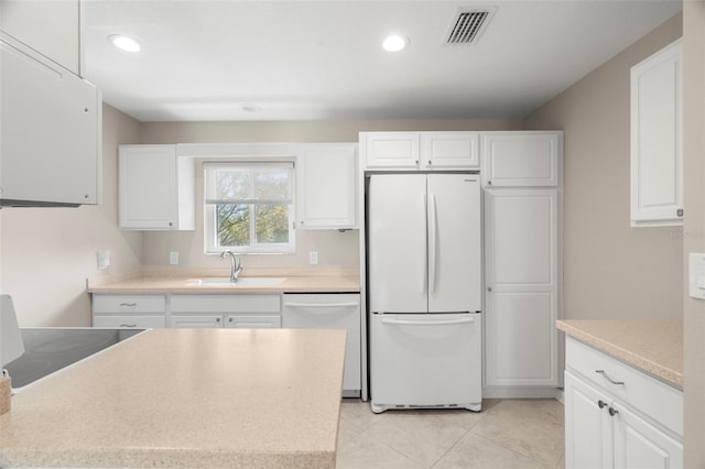 kitchen featuring white appliances, light tile patterned floors, sink, and white cabinets