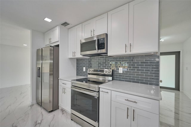 kitchen with appliances with stainless steel finishes, white cabinets, light countertops, and marble finish floor
