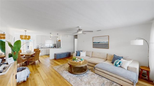 50 154th Ave Unit 50, Madeira Beach, FL 33708 - living room with ceiling fan, light wood-type flooring, and a chandelier