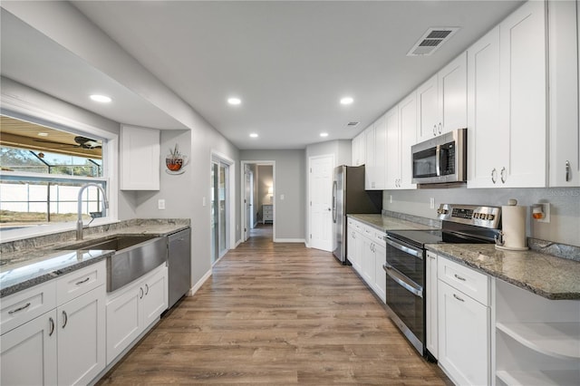 kitchen featuring stainless steel appliances, sink, white cabinets, and dark stone counters