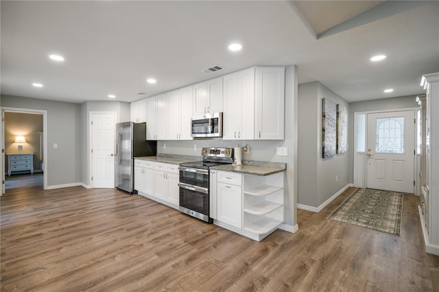 kitchen featuring stone counters, white cabinetry, appliances with stainless steel finishes, and light wood-type flooring