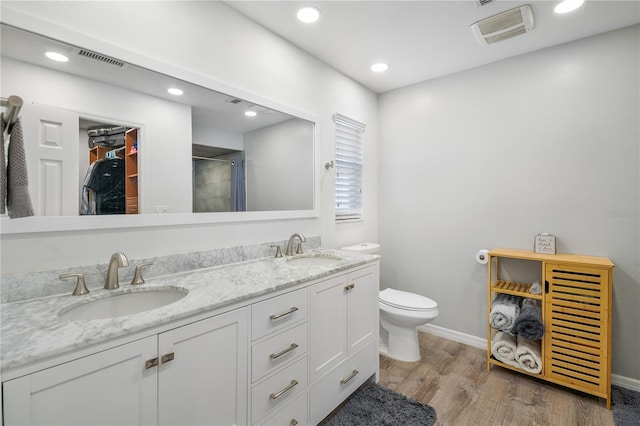 bathroom with vanity, toilet, hardwood / wood-style floors, and a shower