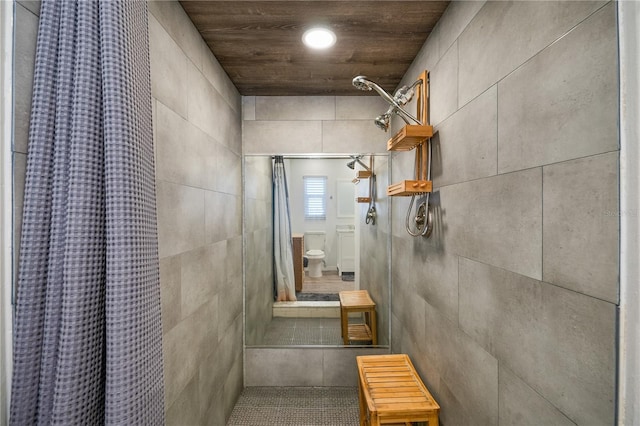 bathroom featuring toilet, curtained shower, and tile walls