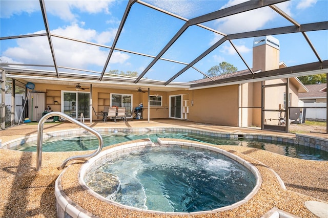 view of swimming pool featuring an in ground hot tub, ceiling fan, a lanai, and a patio area