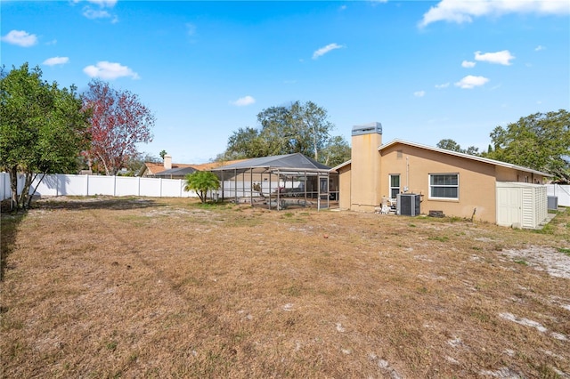 back of house with a lanai, cooling unit, and a lawn