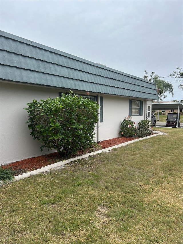 view of side of property featuring a carport and a yard