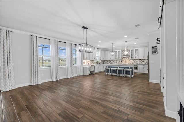 unfurnished living room featuring dark wood-type flooring and ornamental molding