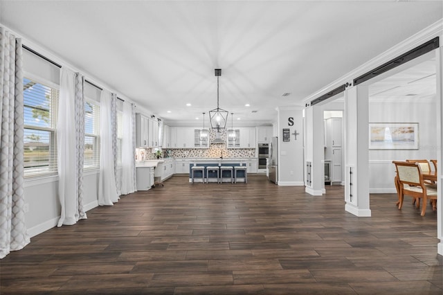 living room with dark hardwood / wood-style floors, a barn door, and a notable chandelier