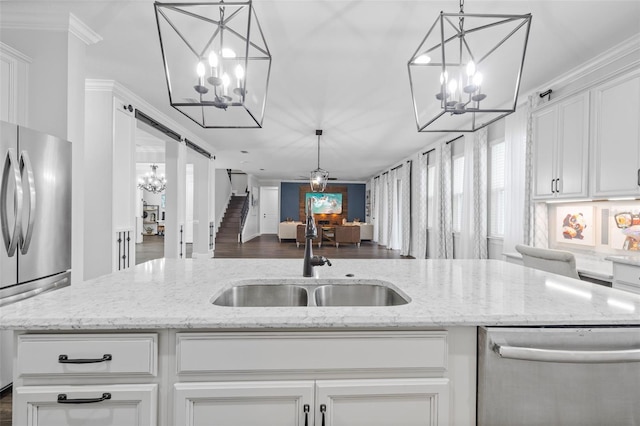 kitchen featuring sink, stainless steel appliances, light stone counters, white cabinets, and a barn door