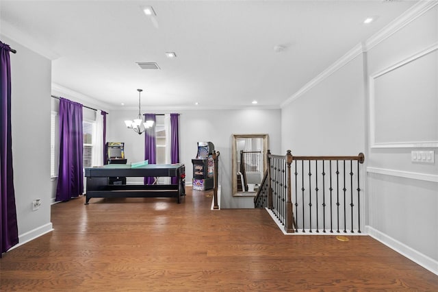 hallway with ornamental molding, hardwood / wood-style floors, and a notable chandelier