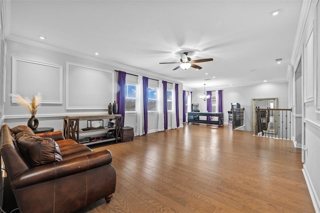 living room featuring ornamental molding, ceiling fan with notable chandelier, and light wood-type flooring