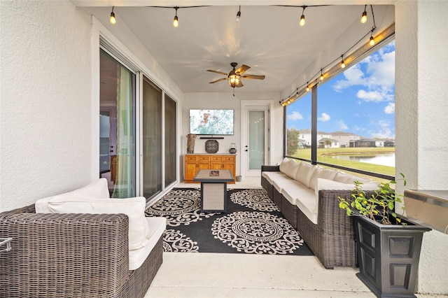 sunroom / solarium featuring ceiling fan and a water view