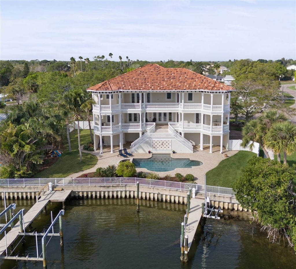 back of property with a patio, a lawn, and a swimming pool side deck with water view