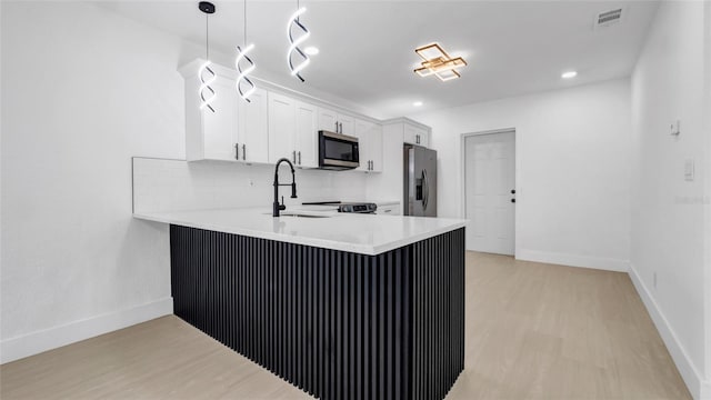 kitchen featuring white cabinetry, stainless steel appliances, decorative light fixtures, and kitchen peninsula