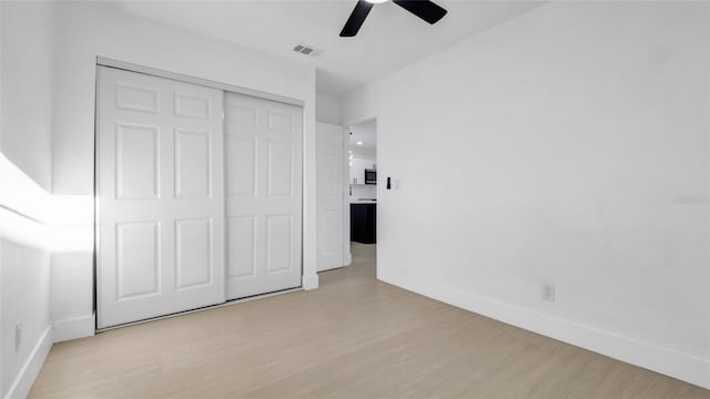 unfurnished bedroom with light hardwood / wood-style flooring, a closet, and ceiling fan