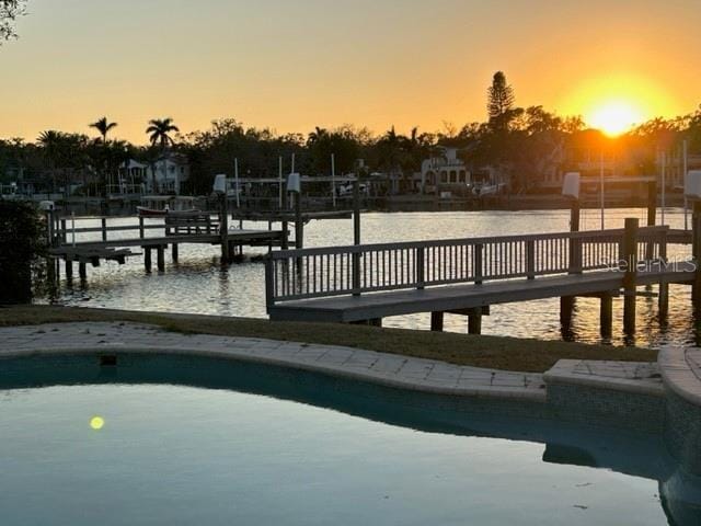 pool at dusk featuring a water view