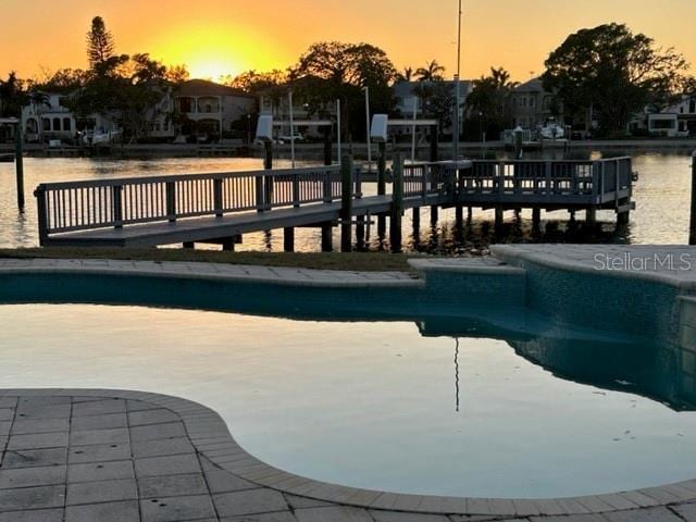 pool at dusk featuring a water view