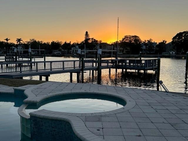 dock area featuring an in ground hot tub and a water view