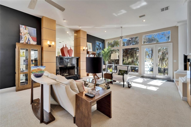 carpeted living room featuring french doors, ceiling fan, and a tiled fireplace