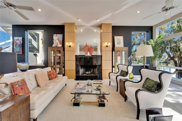 carpeted living room with ceiling fan and a tiled fireplace