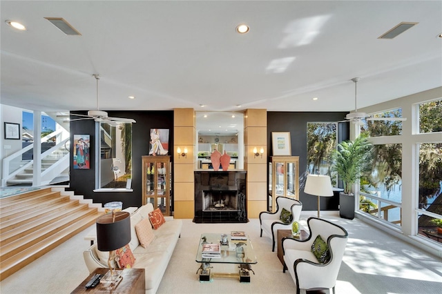 living room featuring a tiled fireplace, light carpet, and a wealth of natural light