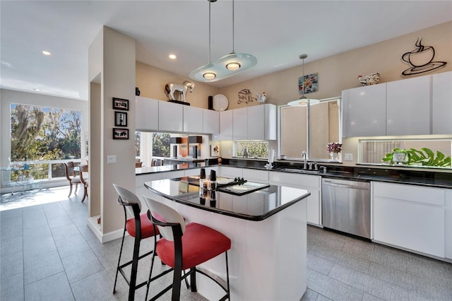 kitchen featuring sink, hanging light fixtures, stainless steel dishwasher, a kitchen island, and white cabinets