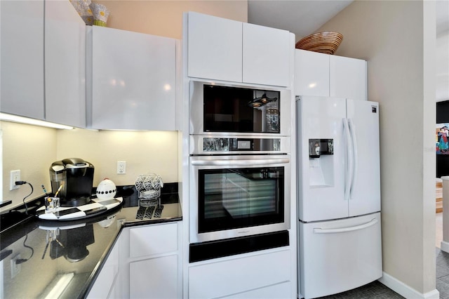 kitchen featuring white cabinets, white refrigerator with ice dispenser, and stainless steel oven