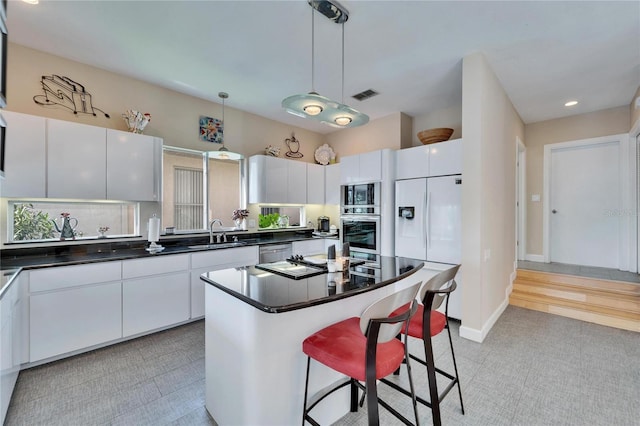 kitchen featuring white cabinetry, a kitchen island, pendant lighting, stainless steel appliances, and decorative backsplash