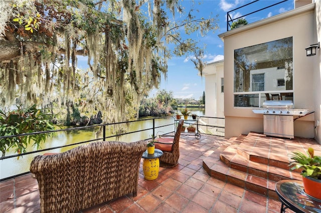 view of patio / terrace with grilling area and a water view