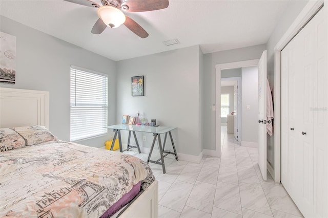 bedroom featuring ceiling fan, multiple windows, and a closet