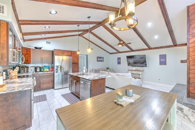 kitchen with ceiling fan with notable chandelier, hanging light fixtures, a kitchen island with sink, stainless steel appliances, and light stone countertops